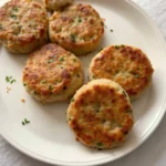 Homemade turkey sausage patties served on a plate with fresh herbs and a side of eggs.