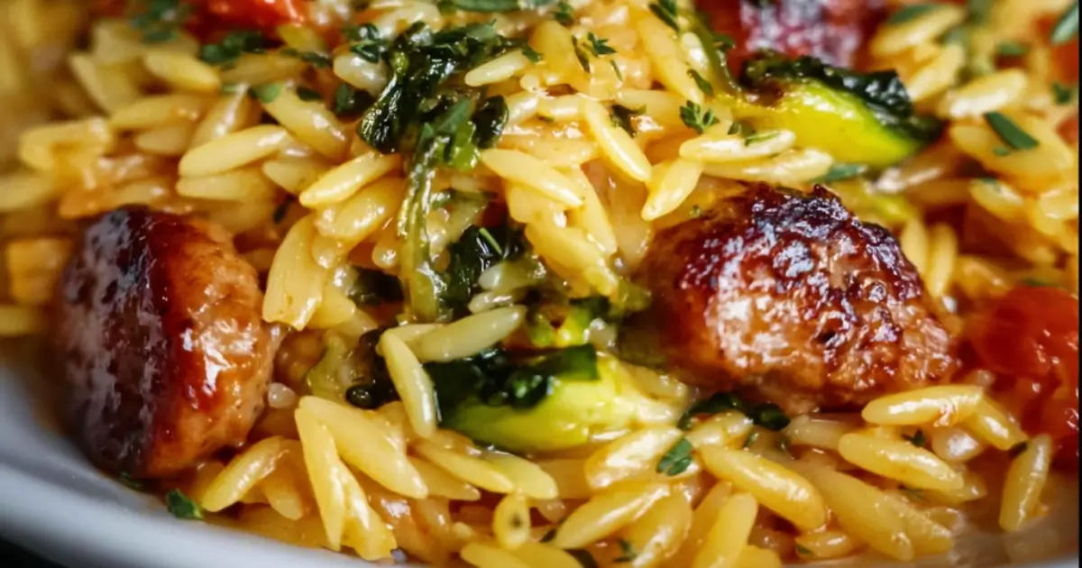 Skillet dinner of golden sausage slices, creamy orzo pasta, and bright green broccoli topped with fresh herbs.