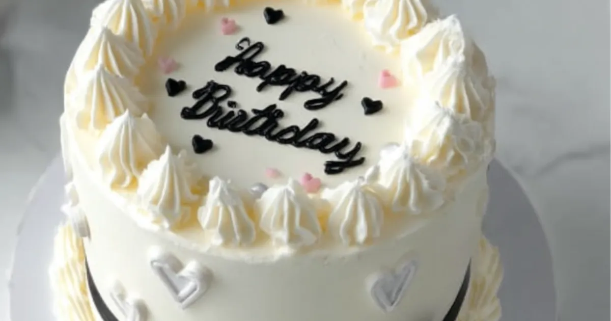 white birthday cake with whipped cream frosting and heart decorations" Title: "Elegant White Birthday Cake with Cream Frosting