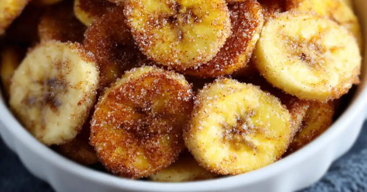 sliced bananas coated in cinnamon sugar served in a white bowl on a textured surface