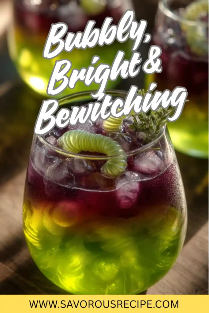 Layered green and purple Halloween cocktail with gummy worms and ice in a glass