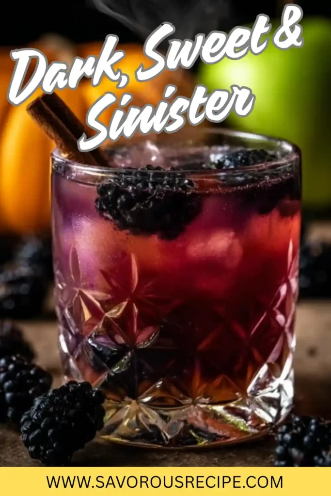 Dark berry cocktail in crystal glass with blackberries and cinnamon stick, surrounded by pumpkins and apples