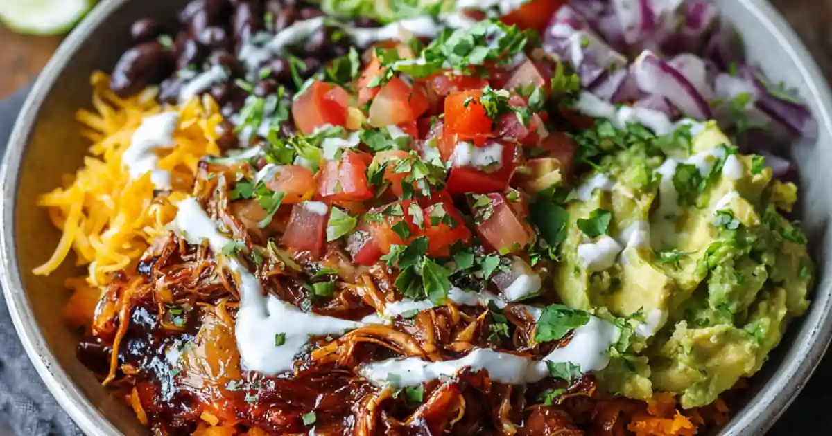 colorful burrito bowl with shredded barbecue chicken, black beans, guacamole, cheese, and fresh pico de gallo