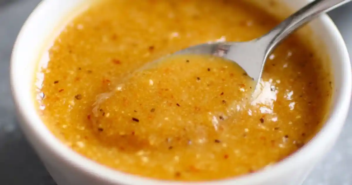 close-up of golden spicy honey garlic sauce with pepper flakes in a white bowl