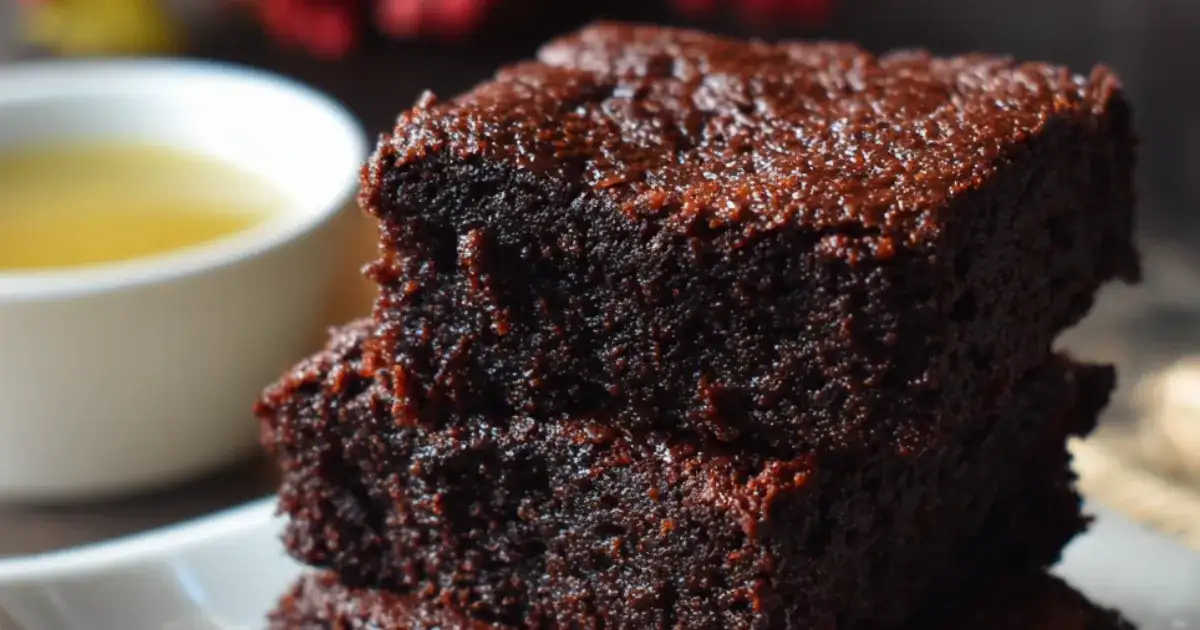 Stack of rich vegan brownies with fudgy texture, served beside a cup of tea