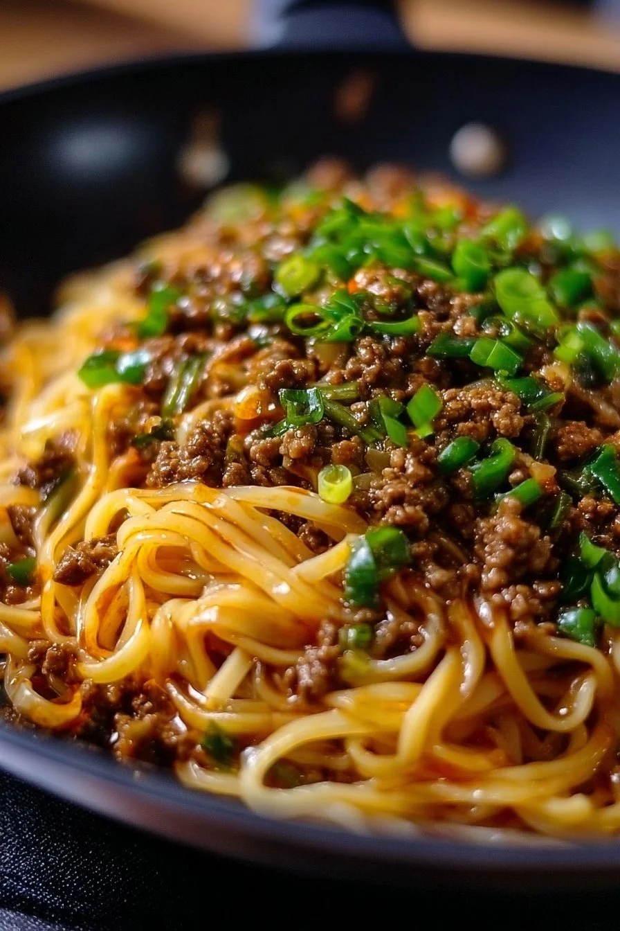 Delicious Mongolian ground beef noodles served in a bowl with fresh vegetables.