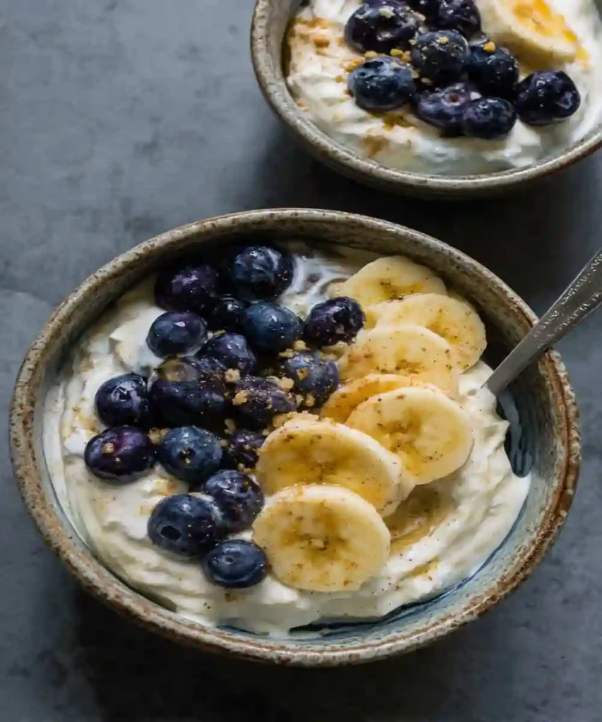 creamy yogurt bowl topped with fresh banana slices, blueberries, and cinnamon