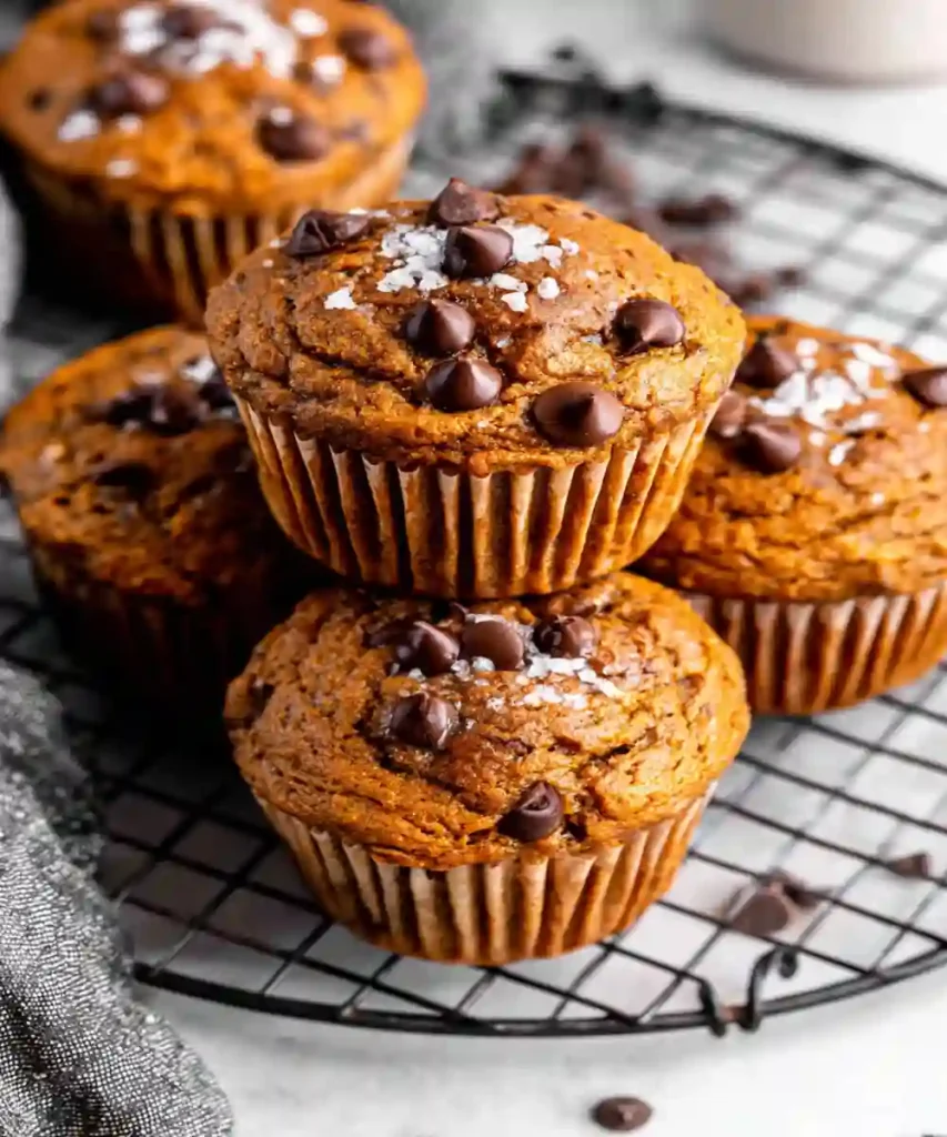 moist banana cinnamon muffins topped with chocolate chips and sea salt on cooling rack