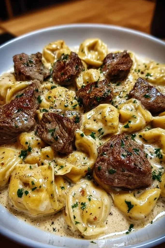 Cracked Garlic Steak Tortellini served in creamy sauce garnished with herbs.