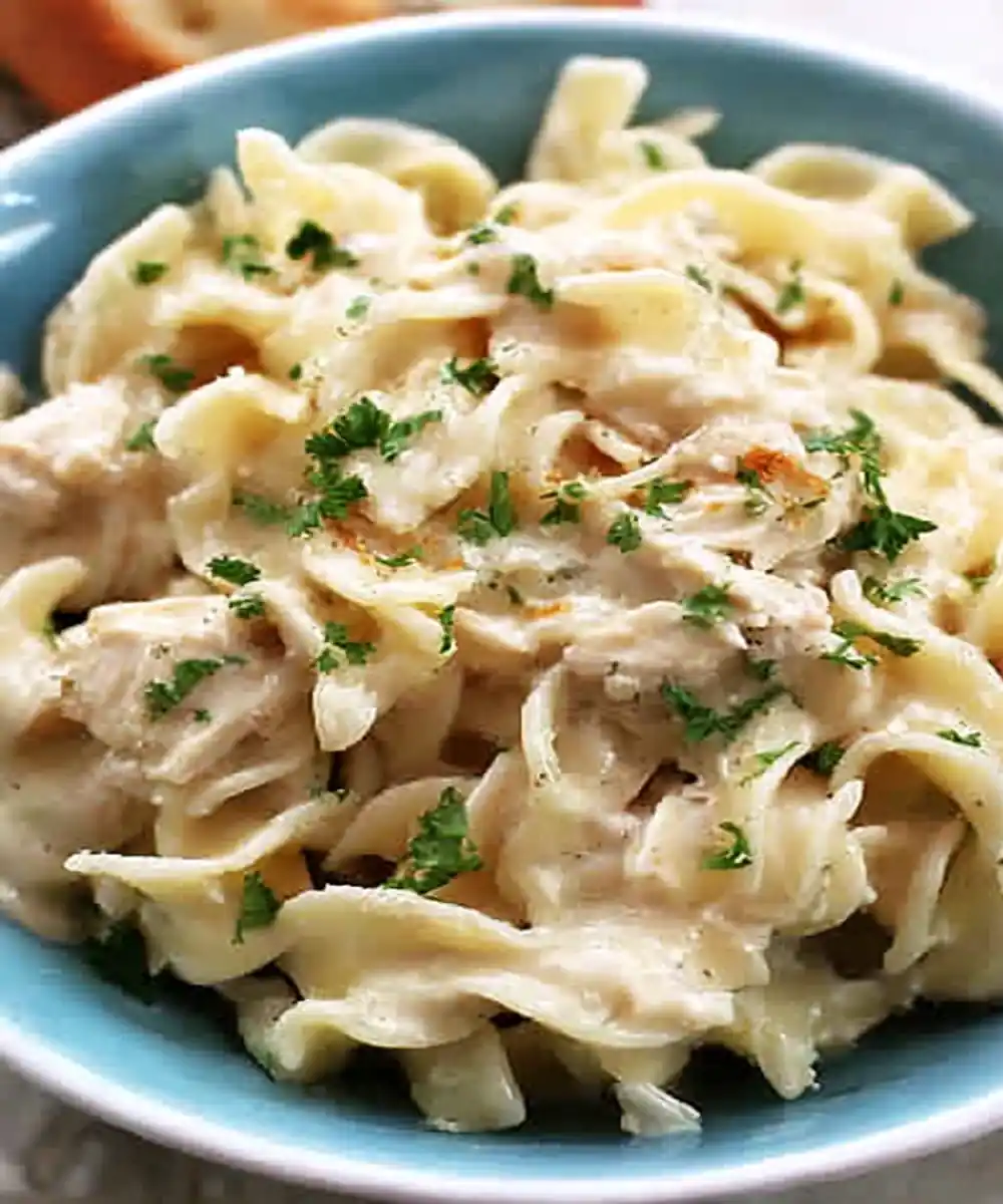 creamy chicken noodle pasta with herbs served in a blue bowl
