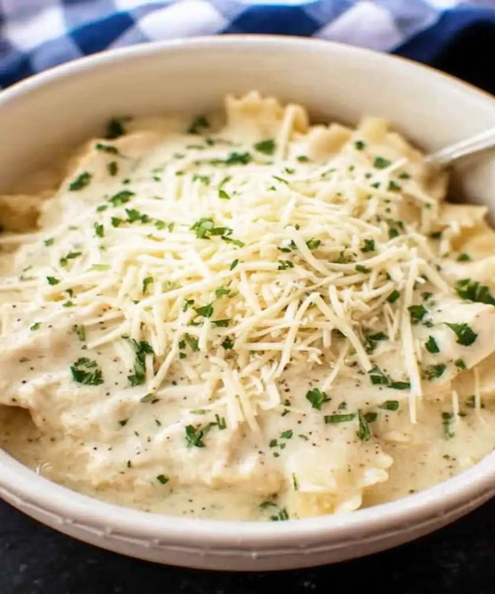 creamy ranch pasta with shredded cheese and parsley in a white bowl