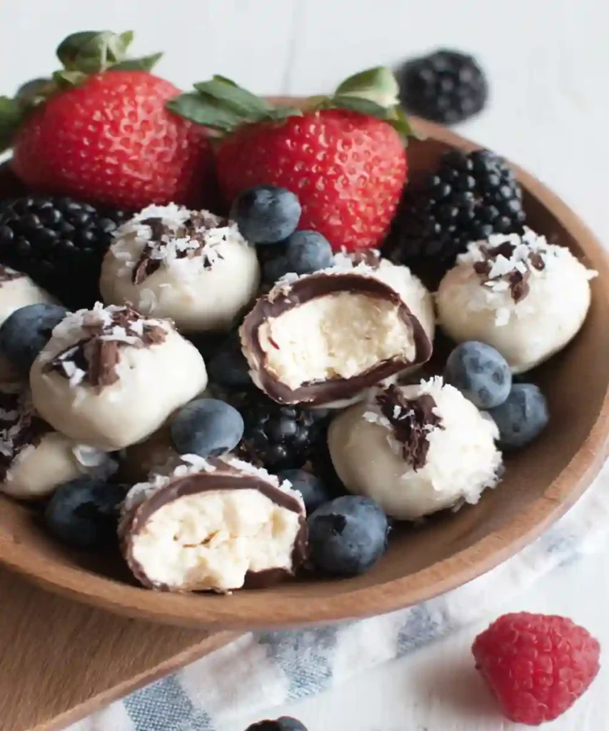 frozen yogurt berry bites with shredded coconut and dark chocolate served with mixed berries