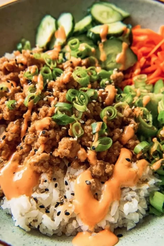Ground turkey rice bowls with Bang Bang sauce garnished with fresh vegetables.