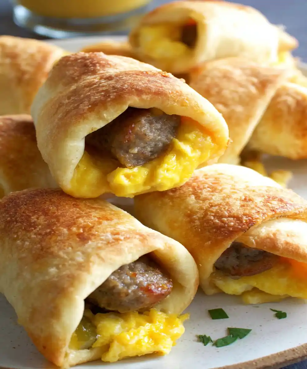 Golden crescent roll-ups filled with scrambled eggs and sausage on a plate