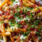 Plate of delicious loaded fries topped with cheese, bacon, and jalapeños