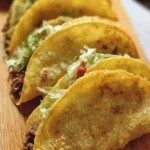 Delicious crunchy beef tacos garnished with fresh toppings and served on a plate