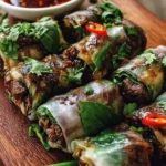 Thai basil beef rolls served on a plate with herbs