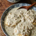 Delicious plate of biscuits and gravy topped with sausage and pepper gravy