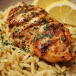 Plate of Greek Lemon Garlic Chicken served with orzo and garnished with herbs