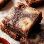 Delicious banana bread brownies topped with chocolate and banana slices.