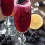 A refreshing Blackberry Mimosa served in a tall glass with blackberries and citrus slices.