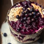 Bowl of blueberry pie overnight oats topped with fresh blueberries and almonds