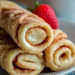 Cinnamon sugar cheesecake roll-ups on a plate, ready to serve.