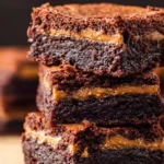 Delicious peanut butter stuffed brownies on a plate with chocolate drizzle.