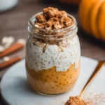 Delicious Pumpkin Cheesecake Overnight Oats topped with whipped cream and spices.