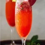A vibrant Strawberry Mimosa Mocktail garnished with fresh strawberries.