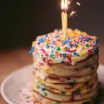 Fluffy birthday cake pancakes topped with sprinkles and whipped cream