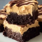 Brownies with creamy peanut butter frosting on top, served on a plate.