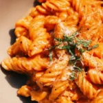 Creamy tomato pasta topped with fresh basil in a bowl