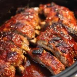 Crock pot barbecue ribs served on a plate with barbecue sauce and garnishes.
