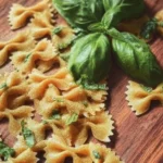 A plate of homemade basil farfalle topped with fresh basil leaves and Parmesan cheese.