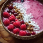 Delicious raspberry smoothie bowl topped with fresh fruits and granola