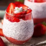 A bowl of strawberry chia pudding topped with fresh strawberries and mint.