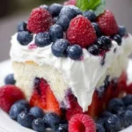 Delicious summer berry poke cake topped with fresh berries and whipped cream.