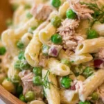 Bowl of tuna pasta salad with vegetables, herbs, and dressing